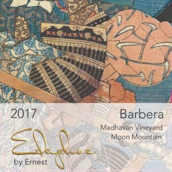 Edaphos Madhavan Vineyard Barbera 2018 label; A rectangular label with ornate abstract design with mixed patterned fabrics in blues, beige, cream and black. The bottom third is overlaid by a transparent white label with gold and black text