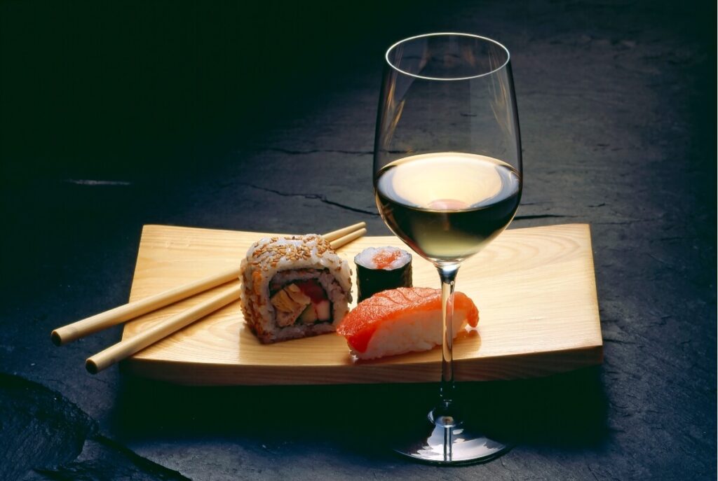 best wine for fish - sushi. sushi and chopsticks with an elegant glass of white wine