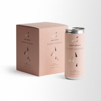 Paper Planes "Flight School" Canned Pinot Noir (4 x 250ml); A white square label showing a box, and one can of wine. Both the box and can are pale pink, with small black, gold and white triangles scattered about.